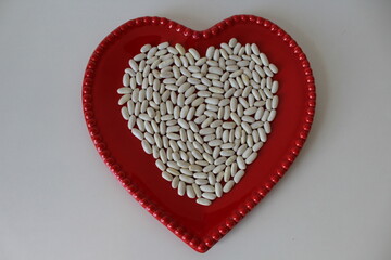 Horizontal photo. Young, raw white beans in a red ceramic bowl. Isolated on a white background. Flat lay. Copy space on the left.