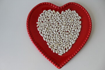 Horizontal photo. Young, raw white beans in a red ceramic bowl. Isolated on a white background. Flat lay. Copy space on the left.