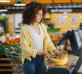 Woman weighing bananas on a scale at the self checkout in supermarket