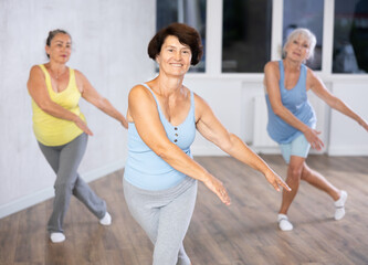 Obraz premium Cheery elderly woman engaged in dancing in fitness studio together with other attendees