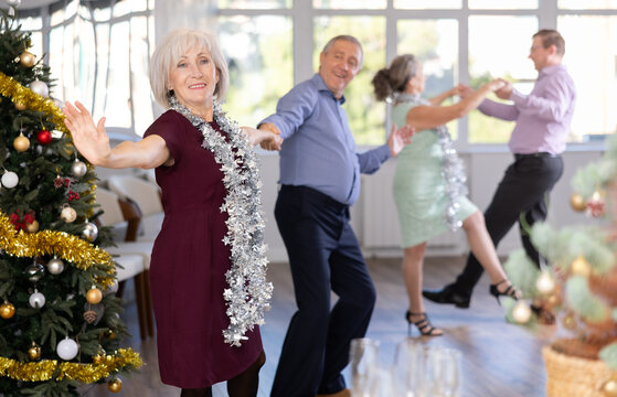 Smiling adult lady in elegant clothes dancing in couple latin dance, energetic and fast jive in modern dance salon during celebration Christmas and New Year