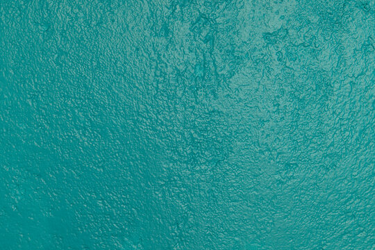 Detalle frontal de muro mexicano pintado de color turquesa vibrante, textura. Concreto decorado con acabado rustico y cacarizo. Pared antigua tradicional con dise&ntilde;o de la epoca colonial.