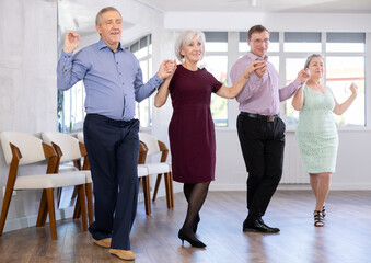 Fototapeta premium Group of men and women dancing traditional folk dance in studio