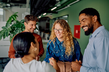Colleagues from diverse backgrounds feeling happy, shaking hands and smiling during a professional meeting in a modern office