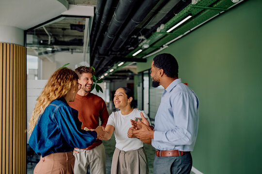 Diverse business people meeting and shaking hands, showing team collaboration and a new partnership forming in a modern office