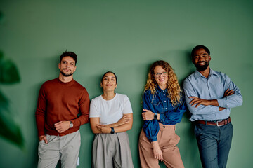 Group of confident diverse business people standing against a green wall, representing teamwork and professional collaboration © we.bond.creations