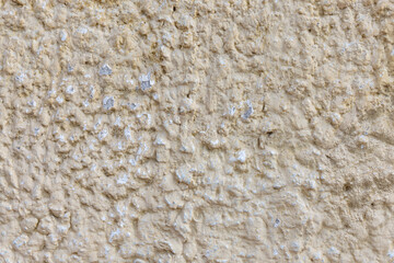 Gran detalle frontal de muro mexicano pintada de color arena, textura muy marcada. Concreto arenoso decorado con acabado rustico y cacarizo. Pared desgastada con diseño de la epoca colonial.