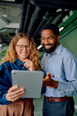 Diverse business colleagues smiling and collaborating, sharing ideas on a digital tablet in a professional corporate workspace