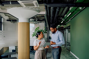 Young diverse business colleagues collaborating on a project, using a digital tablet in a modern office environment