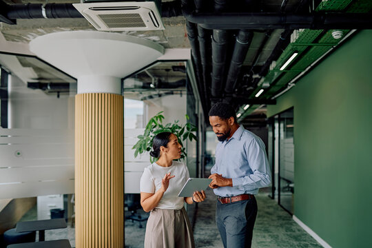 Young diverse business colleagues collaborating on a project, using a digital tablet in a modern office environment - Powered by Adobe