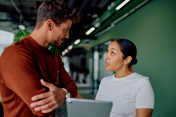 Two business professionals having a serious conversation while collaborating on a project using a tablet in a modern office