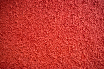 Detalle frontal de muro mexicano pintado de color anaranjado vibrante, textura. Concreto decorado con acabado rustico y cacarizo. Pared antigua tradicional con diseño de la epoca colonial.