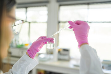 Close up of scientist using pipette with beaker in laboratory
