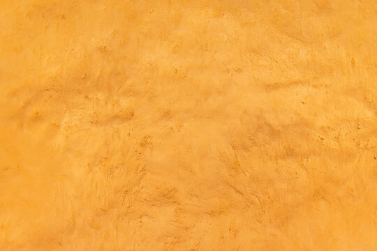 Detalle frontal de muro mexicano pintado de color amarillo vibrante, textura. Concreto decorado con acabado de estuco rustico. Pared antigua tradicional con dise&ntilde;o de la epoca colonial.