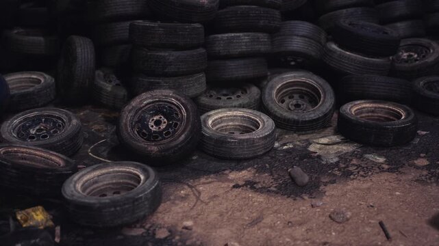 A large collection of worn out tires is stacked in a scrap yard, illustrating urban waste challenges and the ecological impact of tire disposal in a city setting.