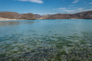 BALANDRA Beach in La Paz, Baja California Sur, Mexico, with crystal clear water and white sand beaches and mountains in the background with a blue sky and clouds