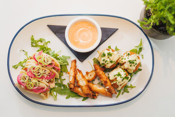 Delicious platter of gourmet appetizers featuring creative toppings and flavorful dips served on a white table