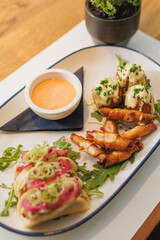 Delicious platter of tacos and crisp appetizers with dipping sauce on a wooden table