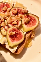 Gourmet toast topped with fresh figs, Camembert cheese, and nuts. Elegant appetizer or snack, perfect for food styling, healthy eating, and rustic cuisine themes.