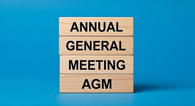 Annual general meeting concept shown with wooden blocks on a blue background for business communication