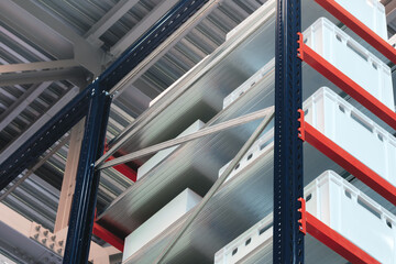 Row of white boxes on a shelf with red dividers. The boxes are stacked on top of each other.