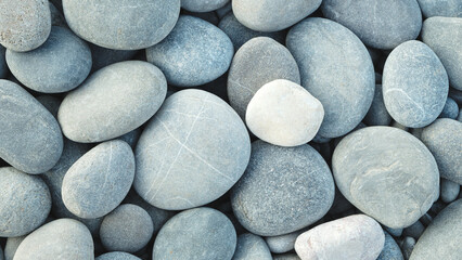 Pebbles stones on seashore as  texture background for design of web banner template page. many stones and they are different in color and size, dry stones illuminated by sun.