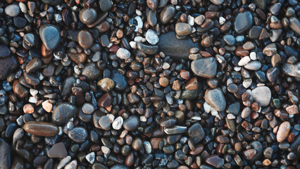 A collection of wet, smooth, multicolored sea stones. The concept of tranquility and serenity serves as a textured backdrop for a web banner page template design.