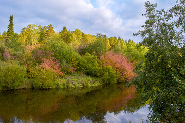 Autumn landscape - forest river and yellowed autumn trees on an autumn evening, autumn landscape scene on a sunny evening.