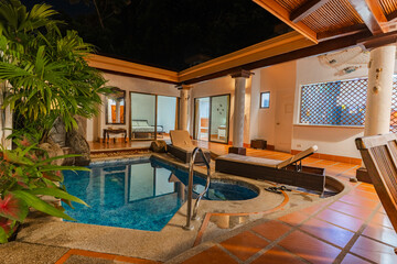 Night view of villa patio with pool and lounge chairs