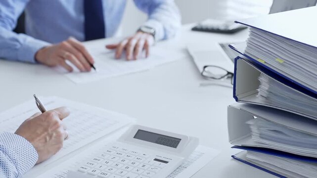 Accountants collaborating on financial reports and strategies while calculating and verifying documents in an office setting. Audit and taxes in business