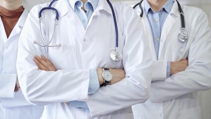 Group of doctors wearing white coats and stethoscopes standing with arms crossed. Medical team at work