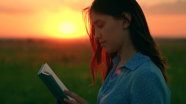 Student reading textbook outdoors in spring. Young woman reading book in autumn park in rays setting sun. Prayer in nature. Man reading book outdoors. Study, education. Beautiful woman praying sunset