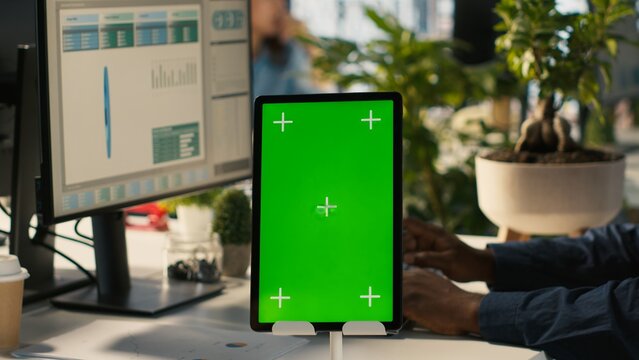 Close up of green screen tablet in front of employee checking progress done on project. Chroma key device next to office clerks reading data statistics on PC screen, camera A - Powered by Adobe