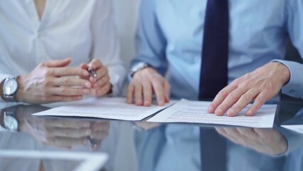 Diverse business people discussing contract papers before signing. Teamwork of lawyers are at work at the glass desk in office