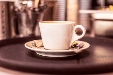 Hot coffee served on a round tray in a cozy cafe setting during morning hours
