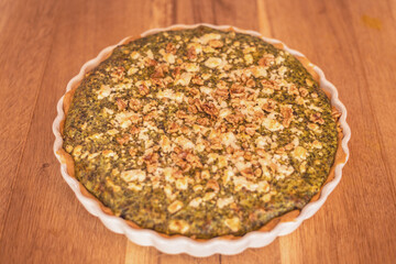 Savory herb tart topped with walnuts on a rustic wooden table perfect for family dinners
