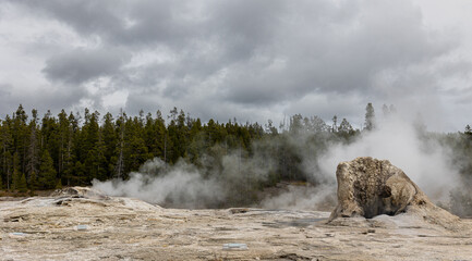 Experience the otherworldly allure of a geyser landscape with rising steam under a dramatic sky,...