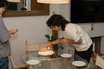 Mujer joven encendiendo candelas en pastel de cumpleaños