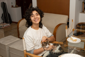 Joven latina soriendo a cámara sentada con un gato en el regazo 