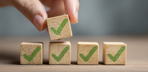 A hand places a small wooden block with a check mark on top of other blocks