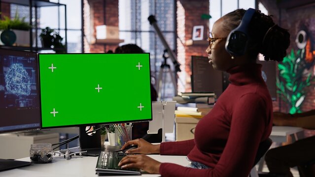African american woman uses mockup PC in AI tech company providing software development services. Startup IT expert uses AI to streamline coding process on green screen PC