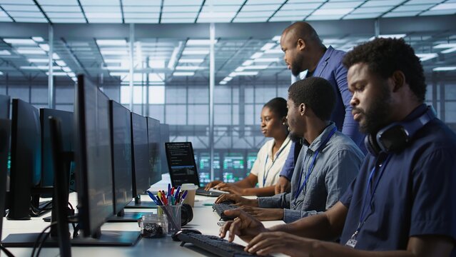 Teamworking computer scientists talking in server room, developing disaster recovery plans. Team of data center office coworkers doing brainstorming, monitoring metrics across devices - Powered by Adobe