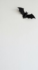 A sleek, three-dimensional black paper bat with intricate folds is elegantly displayed on a bright white surface, offering significant room for text.