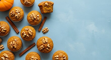 Overhead view of pumpkin muffins with walnuts and cinnamon sticks on blue surface