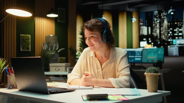 Focused consultant takes notes during executive board meeting video call, extracting essential bullet points from the discussion with business associates. Late night briefing session. Camera A.
