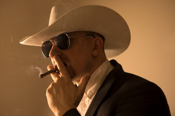 The barded man in a suit holding cigar. Stylish business man on gray studio background. Beautiful male portrait