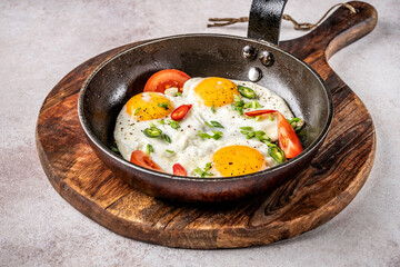 Fried eggs with tomatoes and chili in skillet