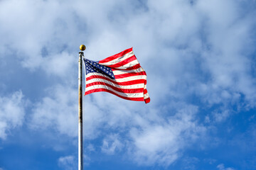 Celebrate independence day, 4th of July, with American flag flying against a sunny blue sky with white puffy clouds, Grand Canyon National Park, Arizona
