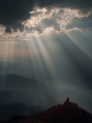 Man sitting on a cliff and admiring breathtaking landscape. Sun rays piercing clouds at sunset. Cinematic light.