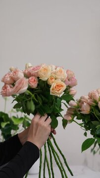 The florist takes a pink Christie bush rose from a vase and forms a bouquet